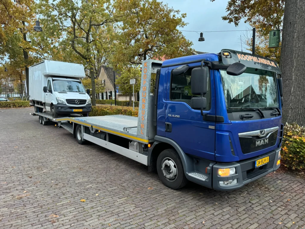 Blauwe MAN-vrachtwagen vervoert witte Mercedes bestelbus op een aanhanger
